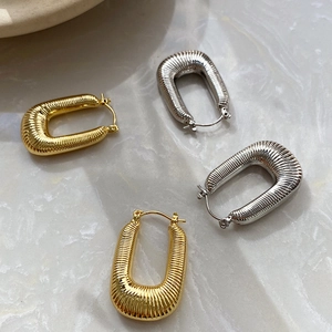 Detail of U-shaped woven gold and silver earrings with vertical pleated textures