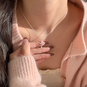 Dettaglio di una collana a croce in argento con zirconi colorati indossata da una modella