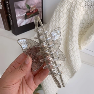 Detail of a butterfly hair claw clip with a grey marble texture and clear spring mechanism