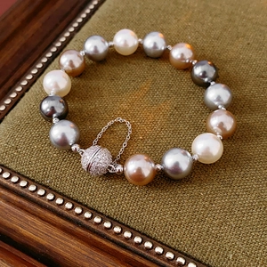 Detail of multi-color pearl bracelet with magnetic diamond clasp on green velvet box