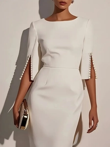 Detailed view of elegant white slim dress featuring pearl-beaded cuffs and side slits