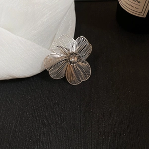 Detailed macro view of silver flower brooch with hollow petals and a sparkling crystal