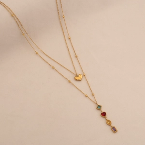Detailed view of gold double-layer necklace with heart pendant and colorful gemstones