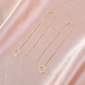 Detailed view of long gold chain threader earrings with hollow circle charms on silk fabric