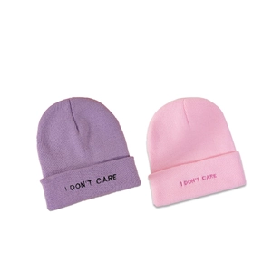 Pink and purple ribbed knit beanies with I DON'T CARE embroidery in a flat lay view