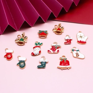Flat lay of 13 Christmas enamel charms featuring bells, socks, and gloves for DIY jewelry