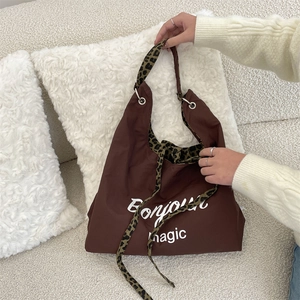 Detail of a brown tote bag with Bonjour magic print and leopard pattern straps