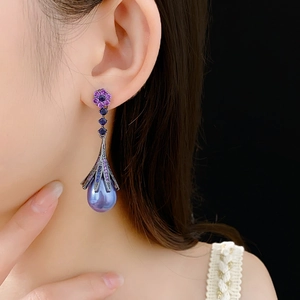 Detailed view of flower earrings with purple petals, blue crystals and teardrop pearls