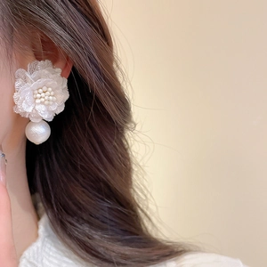 Close-up of elegant white fabric flower earring with small pearls and large pearl drop