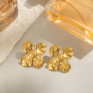 Goldene vierblättrige Blumenohrringe aus poliertem Edelstahl auf grauem Hintergrund