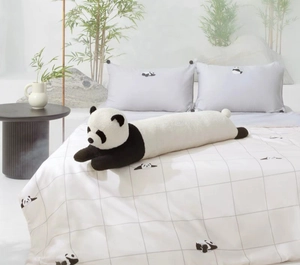Détail d'un long traversin panda en peluche douce sur une parure de lit moderne
