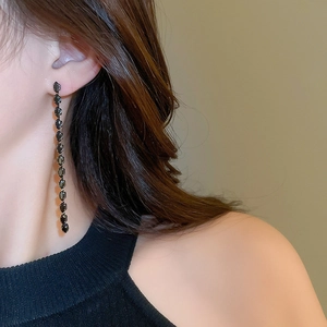 Dettaglio macro di lunghi orecchini a nappa in zircone nero con eleganti perline geometriche
