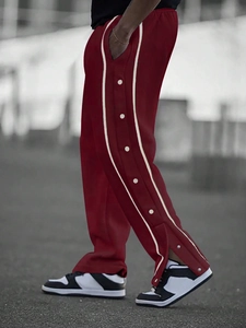 Detail of red joggers with side snap buttons and white stripes on outdoor model