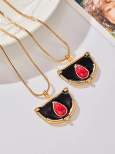 Détail du pendentif roue de ferris avec émail noir et pierre rouge sur chaîne dorée