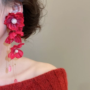 Detail of red fabric flower earrings with crystal tassels and pearl center on a model