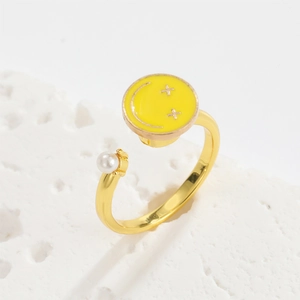 Close-up of rotatable daisy ring with yellow smiley face enamel and white pearl
