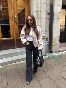 Chic beige zip-up bomber jacket with pleated peplum hem paired with black wide-leg trousers