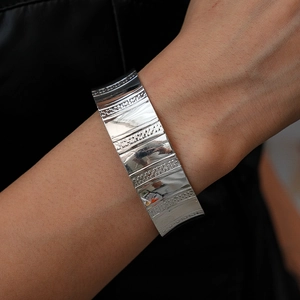 Vue macro d'un bracelet large argenté avec des rayures polies et des motifs texturés