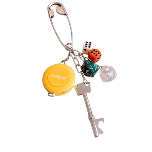 Unique safety pin keychain with a mini yellow tape measure, silver key, and colorful dice