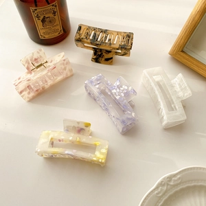 Five marble-patterned acrylic hair claws in varied colors on a clean white background