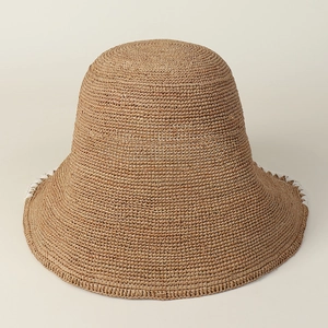 Detailed close-up of natural raffia straw hat with white stitched brim for women