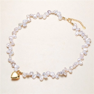 Detailed view of Baroque pearl necklace with a golden heart pendant and lobster clasp