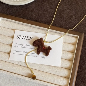Detailed close-up of a flocking horse pendant necklace with a tiger eye stone bead