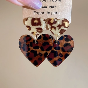 Nahaufnahme herzförmiger Harzohrringe mit Leopardenmuster auf einer Vintage-Karte