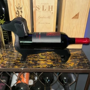 Creative black dachshund wine bottle holder stand on a shelf with cellar background