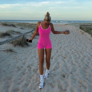 Gros plan du combishort dos nu en maille rose sur une plage au coucher du soleil