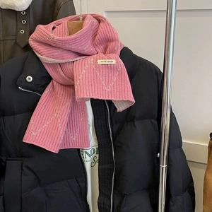 Detail of pink knitted scarf with gray geometric patterns and handmade label on jacket