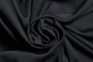 Macro shot of black knitted fabric texture showing elasticity and high quality draping
