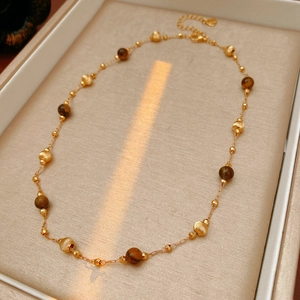 Primo piano della collana di perle occhio di tigre placcata oro con ciondolo a cuore