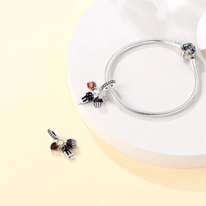 Close-up of silver charm bracelet with colorful dessert pendants and cupcake charms