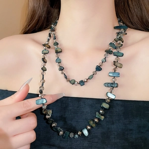 Detailed macro view of long layered necklace with iridescent shells and faceted crystal beads