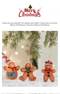 Close-up of resin gingerbread man ornaments with colorful scarves on a snowy pine branch