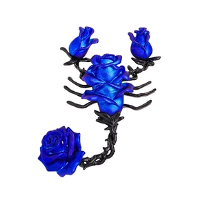 Detailed view of scorpion brooch featuring blue roses and black vine legs on white background