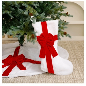 Detail of plush white Christmas stocking and tree skirt with festive red velvet bows
