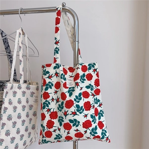 Detail of vintage red rose floral pattern on a cotton canvas tote bag hanging on a rack