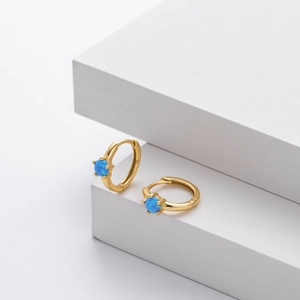 Close-up of gold S925 silver hoop earrings with blue opal on white geometric blocks