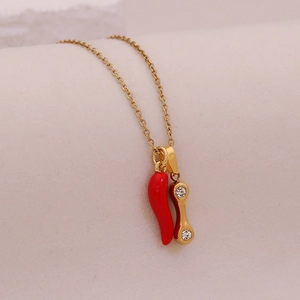 Detail of gold chain necklace with red enamel chili and rhinestone bone pendant charm
