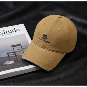 Detailed embroidery on khaki cotton baseball cap featuring blue HB logo on leather surface