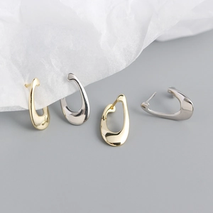 Detail view of abstract teardrop metallic earrings in gold and silver polished finishes