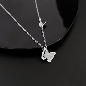 Detail of silver titanium butterfly pendant with layered polished and matte textures