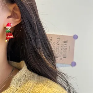 Close-up of model wearing handmade beaded Christmas hat earrings with festive red bells