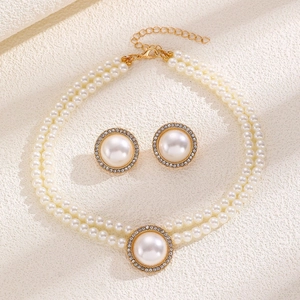Detail of elegant gold pearl jewelry set including a necklace and matching round earrings