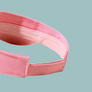 Detail view of pink sun visor featuring reinforced stitching and breathable cotton fabric