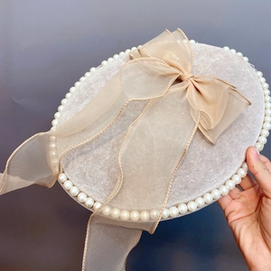 Close-up of beige velvet hair clip with faux pearl trim and sheer organza bow detail