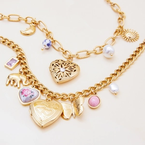 Detailed shot of gold multilayer bracelet with heart locket, elephant and moon charms