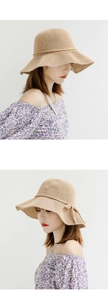 Detail showing the natural knit texture and decorative knot of the beige sun hat